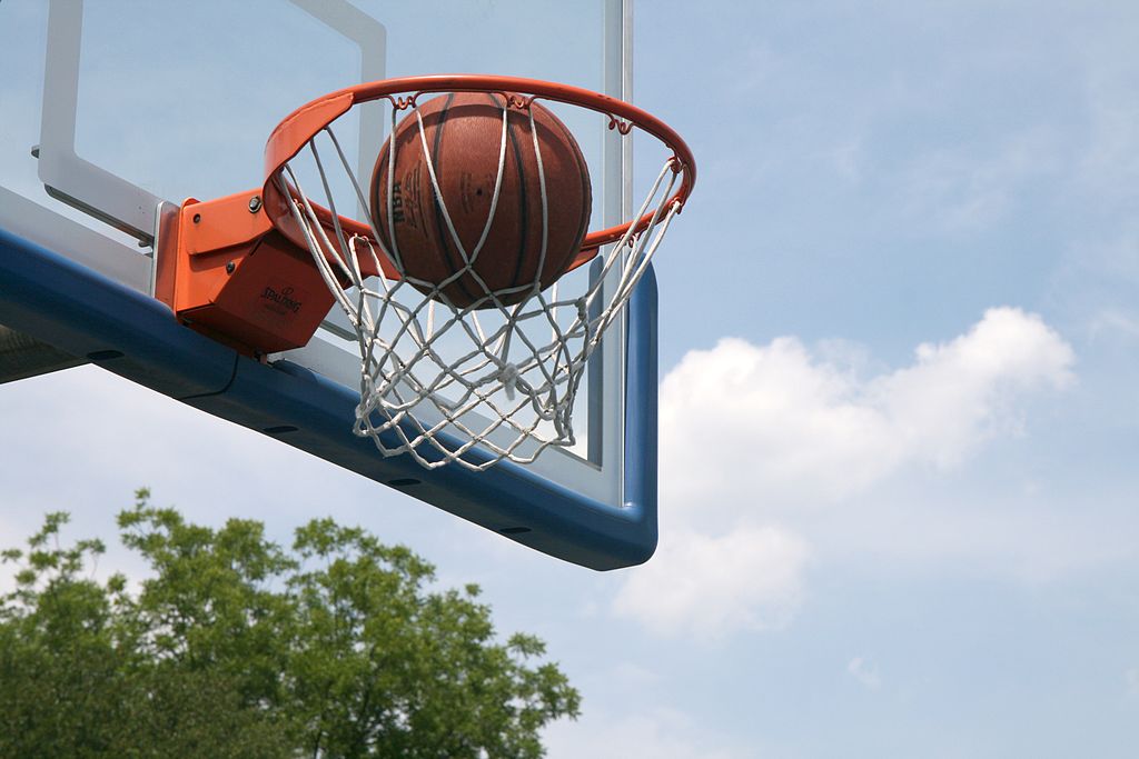 Basketball Ball about to fall through the hoop at a court that shows kinetic energy exerted by the player