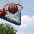 Basketball Ball about to fall through the hoop at a court that shows kinetic energy exerted by the player