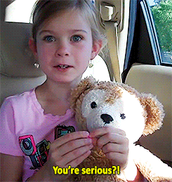 unsure looking girl holding a teddy bear in the car