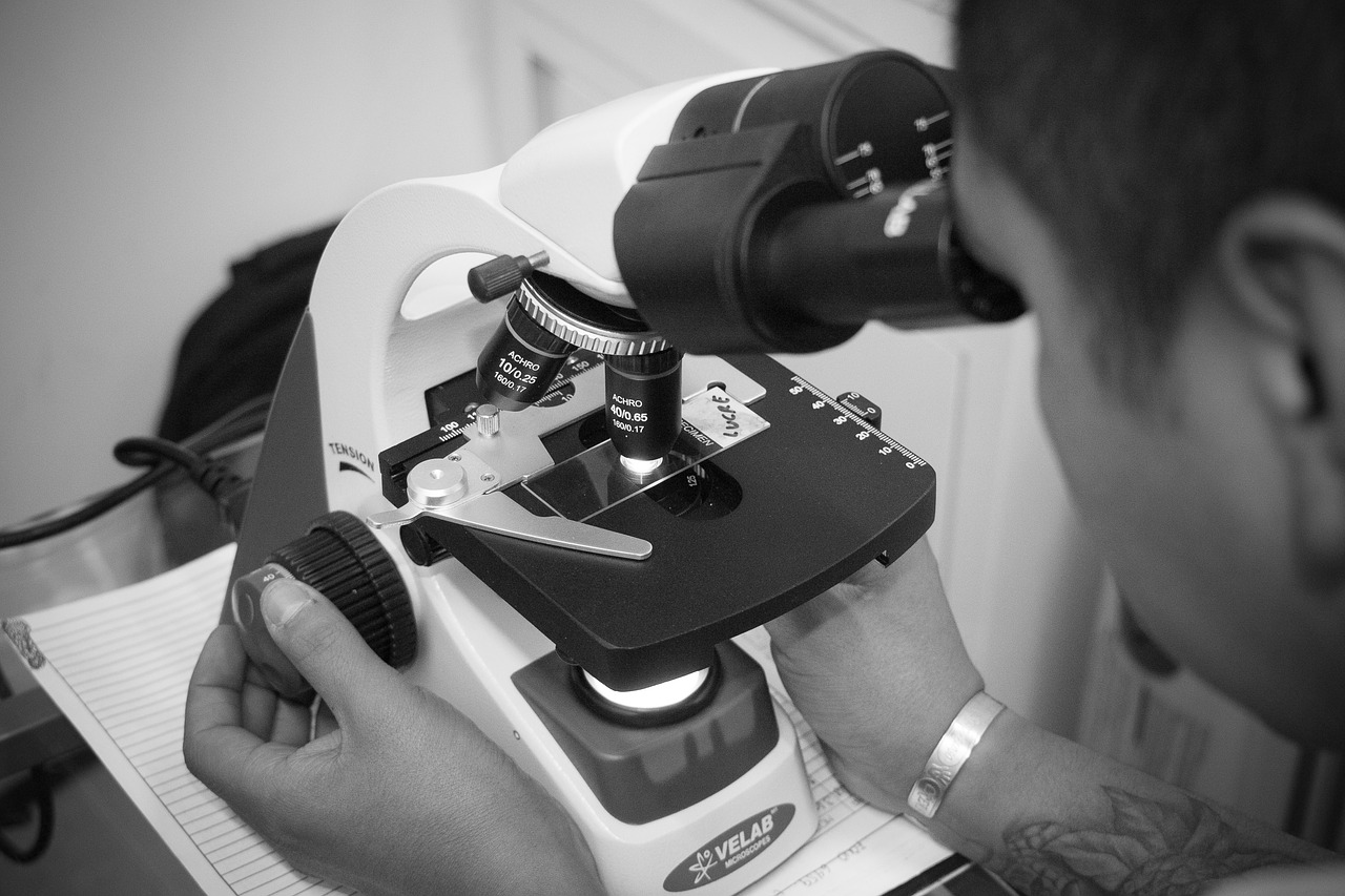 black and white photo of adult using a microscope